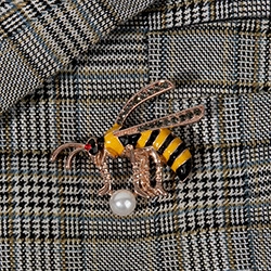 Detail of a luxury gold bee brooch with pearls on a grey plaid blazer jacket