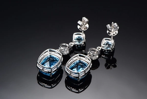 Detail of square-cut blue gemstone earrings with diamond accents and silver backing