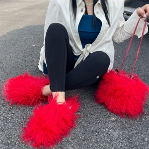 Detail of red long faux fur bucket bag and matching plush mules set in lifestyle setting