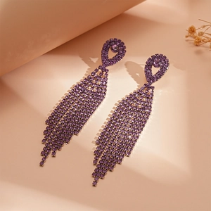 Detailed view of long purple tassel earrings with pave-set rhinestones in a lifestyle setting