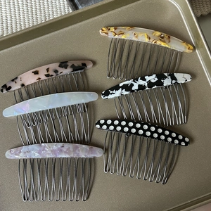 Assorted acetate hair side combs in tortoise and marble patterns on a metal tray
