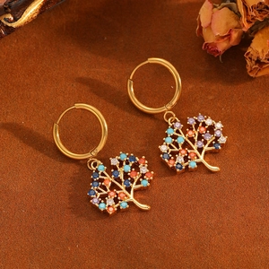 Golden Tree of Life earrings with colorful rhinestones on a warm textured background