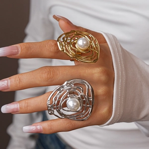 Detailed view of chunky gold and silver irregular spiral rings with faux pearl inlay