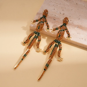 Detailed close-up of gold gecko earrings with vibrant orange and green crystals on stone