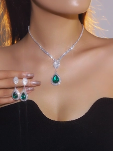 Close-up of bridal jewelry set with pear-shaped green gemstones and silver rhinestones