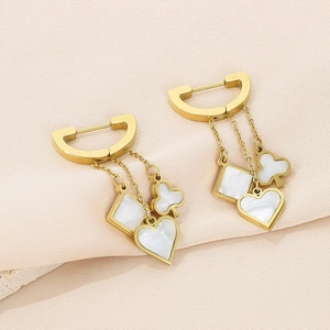 Close-up of heart and clover charms in white shell inlay on golden titanium steel earrings