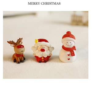 Close-up of resin Santa Claus, reindeer, and snowman figurines on soft plush background