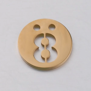 Vue macro d'un pendentif circulaire en acier doré avec découpe chiffre huit et deux trous