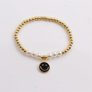 Detail of beaded gold chain bracelet with white pearls and black smiley face charm