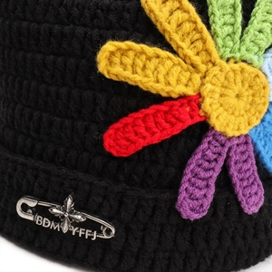 Black cat ear knit hat with colorful crochet flowers and a silver metal safety pin