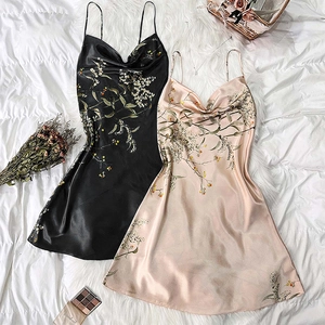 Floral print silk satin slip dresses in black and champagne pink on white sheets