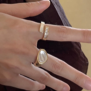 Detail showing two gold open rings with mother of pearl inlays and sparkling zircons