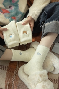 Detail of warm off-white fleece socks featuring cute fox and rabbit animal embroidery