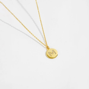 Macro detail of S925 sterling silver gold-plated disk pendant with zircon letter M
