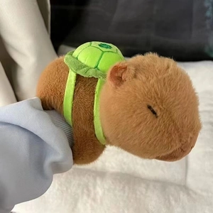Close-up of a Capybara plush bracelet with a green turtle backpack on a person's wrist