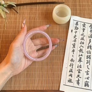 Close-up of translucent pink glass bracelet worn by a model in a traditional style setting