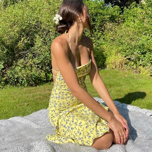Detail of yellow floral sundress with backless design and slit on the grass