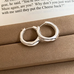 Close-up of silver irregular flower earrings on a velvet jewelry box with book background