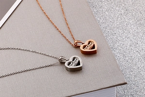 Close-up of heart-shaped mama pendant necklaces in rose gold and silver finish