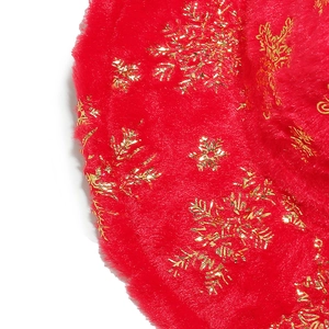 Detailed close-up of red plush fabric featuring metallic gold snowflake patterns
