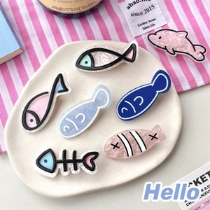 Close-up of cute acrylic fish-shaped hair clips and dolphins in a ceramic tray