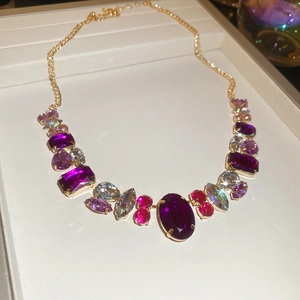 Detailed macro view of gold chain necklace with colorful oval and marquise gemstones