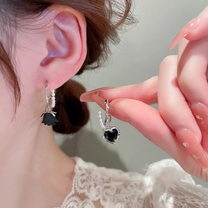 Close-up of asymmetric black rose and heart dangle earrings with pearl details