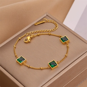 Elegant gold titanium bracelet featuring square emerald zircon stones on jewelry box