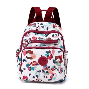 Multi-pocket nylon backpack for women with colorful abstract print and burgundy straps
