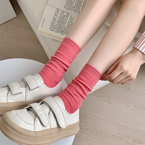Pink cotton ribbed mid-calf socks paired with white platform velcro sneakers on wood floor