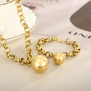 Gros plan d'un collier et d'un bracelet en acier doré avec de grandes perles polies lisses