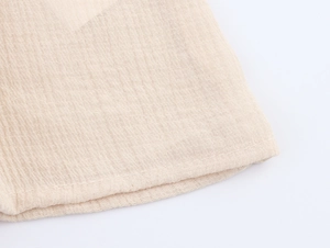 Macro detail of beige embroidered short shirt showing textured seersucker fabric and stitching