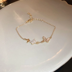 Detail of gold butterfly bracelet with zircons and mother of pearl on a ceramic plate