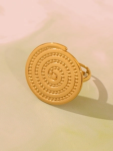 Detail of a golden spiral ring featuring intricate beaded textures and a polished finish