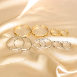 Macro view of gold and silver stainless steel hoop earrings in three sizes on silk