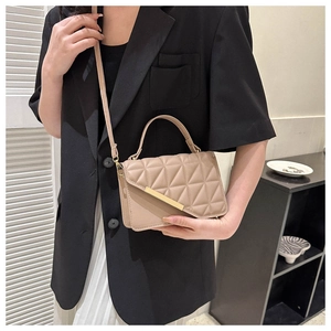 Dettaglio borsa a mano trapuntata beige con decori dorati e tracolla