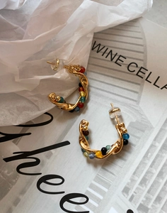 Detail of vintage C-shaped earrings with colorful stone beads and twisted gold wire design