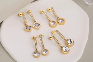 Detail view of gold geometric earrings with Roman numerals and cubic zirconia on tray