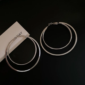 Gros plan de boucles d'oreilles doubles anneaux argentés avec texture polie géométrique