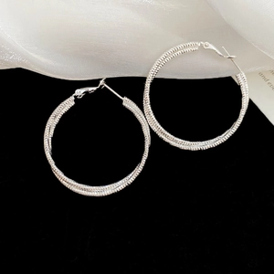 Detail showing the intricate spiral woven texture of silver hoop earrings for women