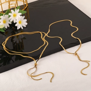Adjustable gold titanium snake chain necklace set with tassel charm on artistic background
