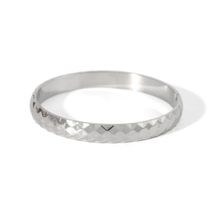 Macro view of silver stainless steel bangle showing precision diamond-cut geometric texture