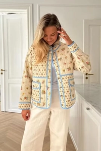 Close-up of floral quilted jacket featuring blue piping details and front button closure