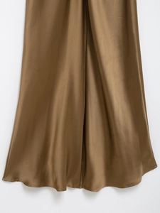 Detail showing the glossy bronze satin fabric texture and flowing hem of the maxi dress