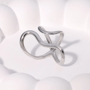 Macro shot of silver irregular wavy cross-line stainless steel ring on a white tray