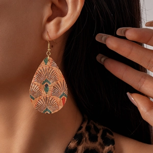 Gros plan de boucles d'oreilles goutte en cuir avec motif plume de paon et crochet doré