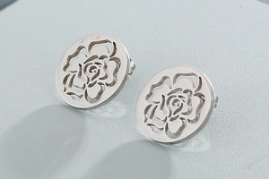 Detailed close-up of silver hollow rose stud earrings with intricate floral design