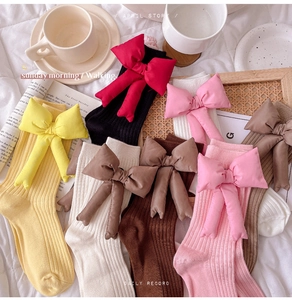 Detailed flat lay of colorful cotton slouch socks featuring oversized decorative 3D bows
