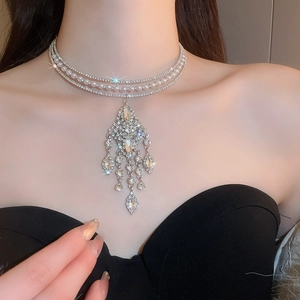 Macro detail of luxury choker necklace with layered pearls, rhinestones and tassel pendant