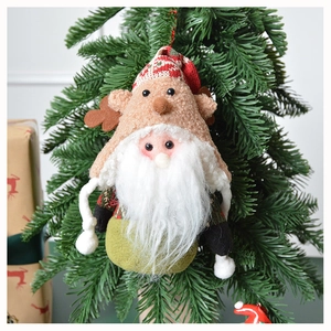 Detail of Christmas plush ornament with reindeer antlers and knit hat in festive setting
